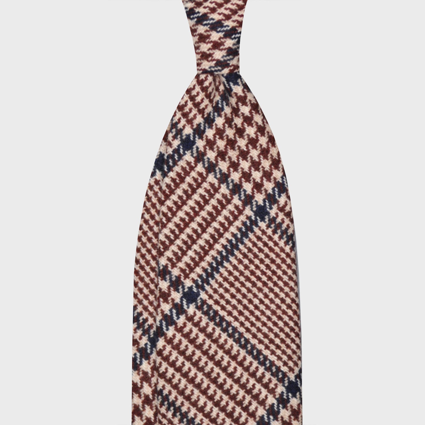 Denim Blue Wool Tweed Gun Club Handmade Men's Tie. Tweed wool tie switzerland F Marino ties for Wools Boutique Uomo, light tweed soft texture to the touch, ivory white and brown background, blue windowpane tie