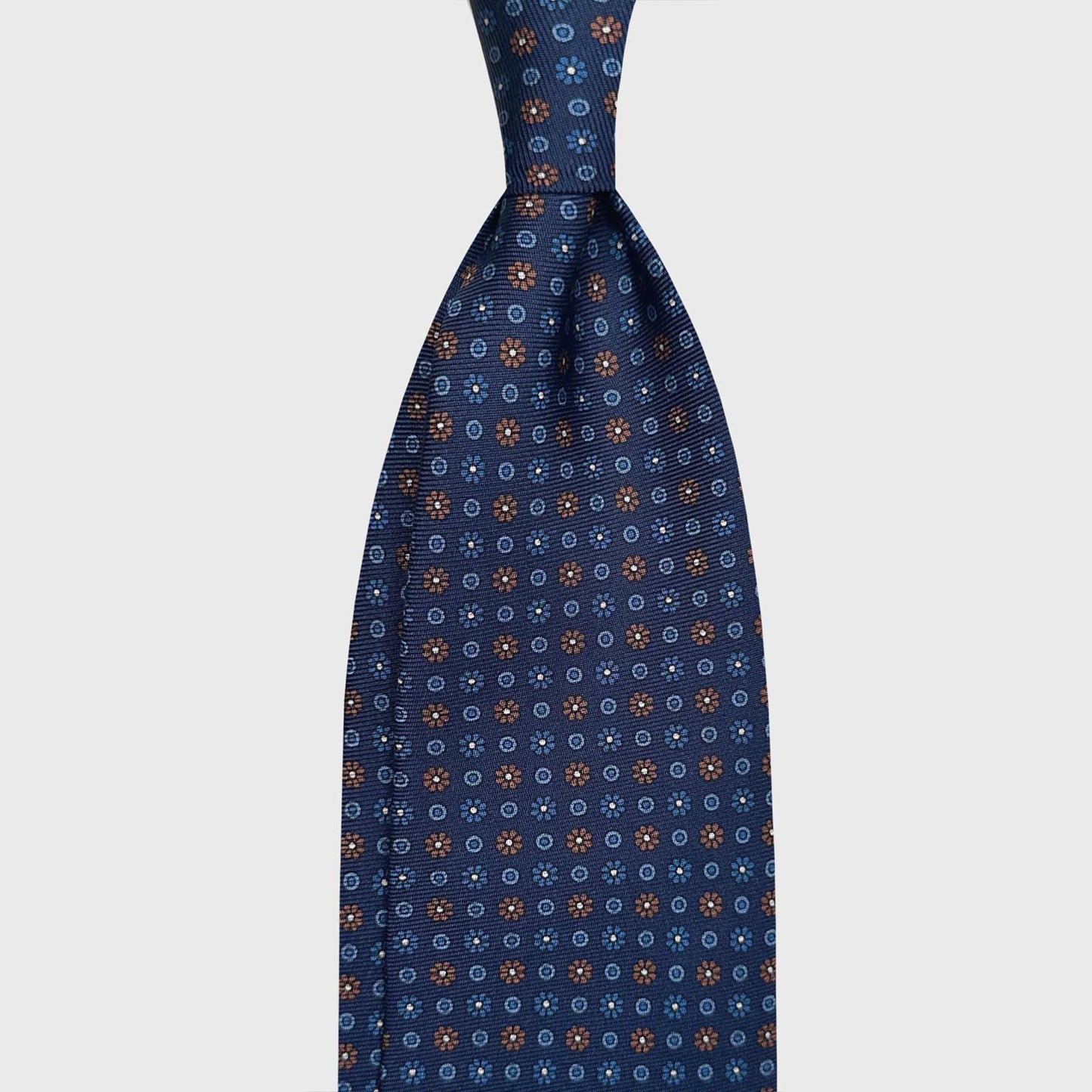 Classic Blue Madder Silk Tie 7 Fold Brown Micro Daisy. Elegant silk tie with blue background and brown and light blue micro daisy pattern, seven folds silk ties F.Marino Napoli for Wools Boutique Uomo Genève