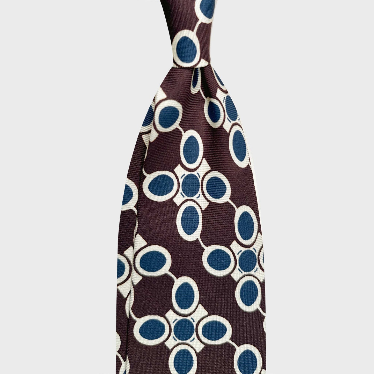 Coffee Brown Silk Tie Art Deco Atomic Pattern 50s Industrial Design. Coffee brown silk tie featuring an Art Deco atomic pattern in white and petrol blue, inspired by 1950s industrial design and modernist interiors. Wools Boutique Uomo men's ties store in Geneva.