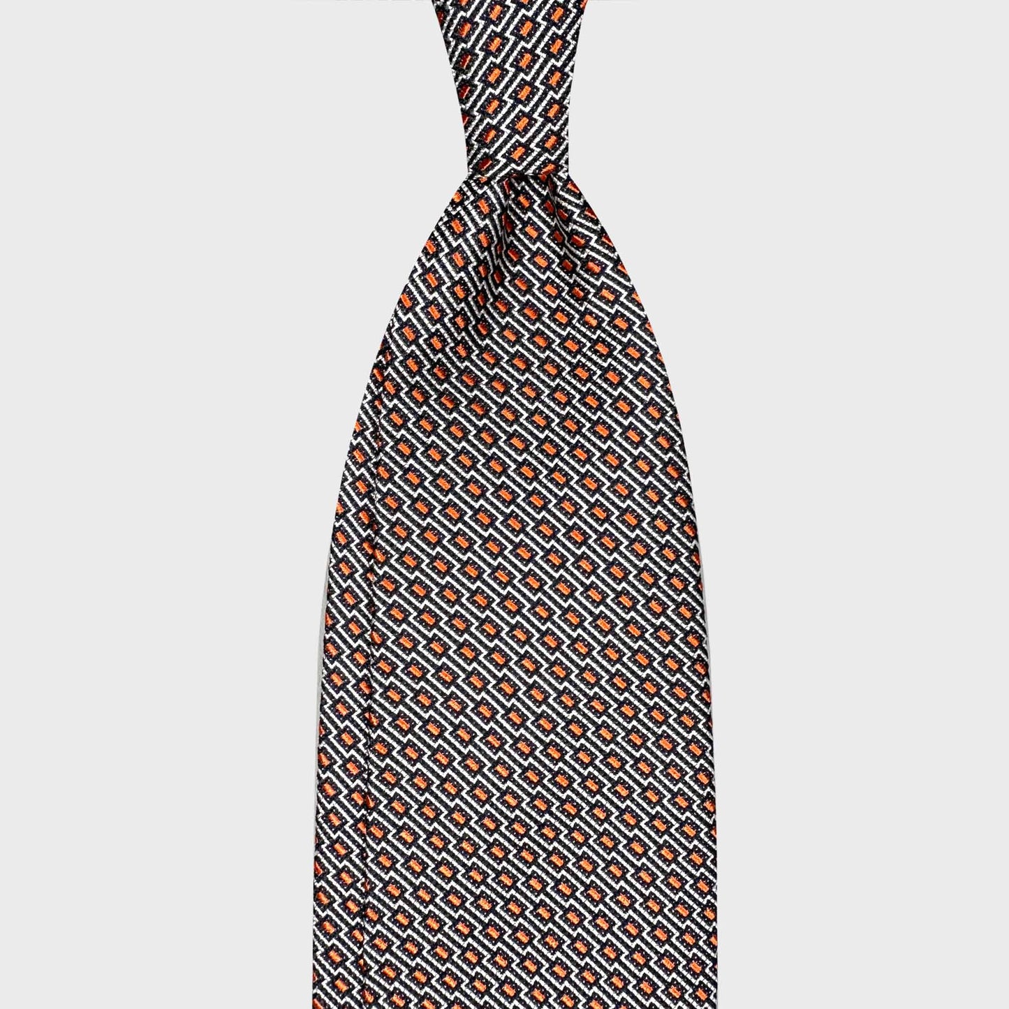 Orange Silk Tie Art Deco Geometric Best Men’s Store Geneva. Orange silk tie with refined Art Deco geometric pattern, handmade in Italy. Discover elegant ties at Wools Boutique Uomo Geneva.