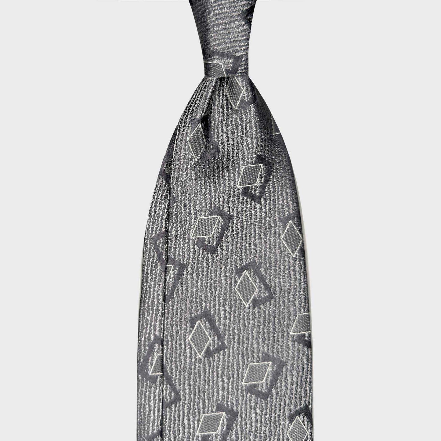 Mens Grey Silk Tie Art Decò Geometric Pattern. Silver grey silk tie with Art Déco geometric motifs in anthracite and white. Handmade in Italy and selected by Wools Boutique Uomo Geneva.