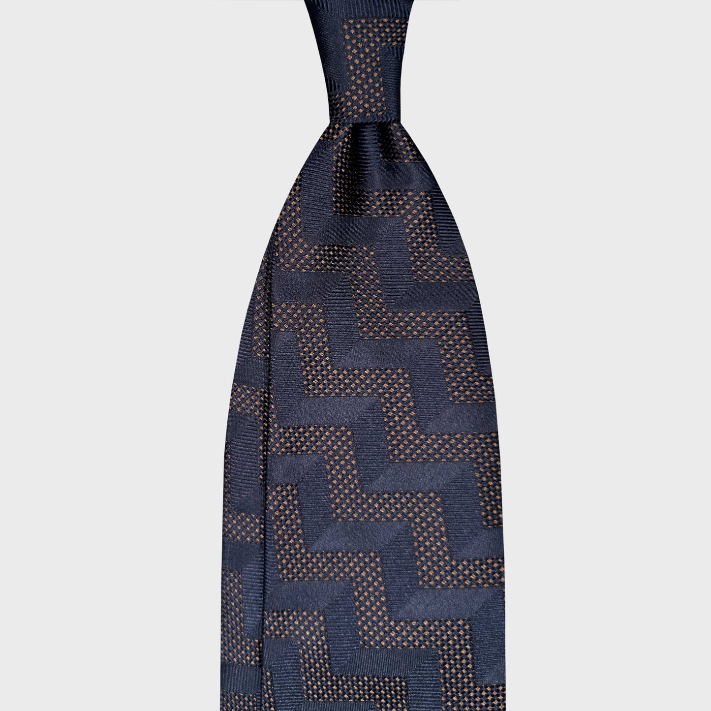 Mens Navy Blue Tie Art Decò Zig Zag Geometric Pattern. Navy blue silk tie with Art Déco zig zag pattern and brown melange texture. Handmade in Italy and selected by Wools Boutique Uomo Geneva.
