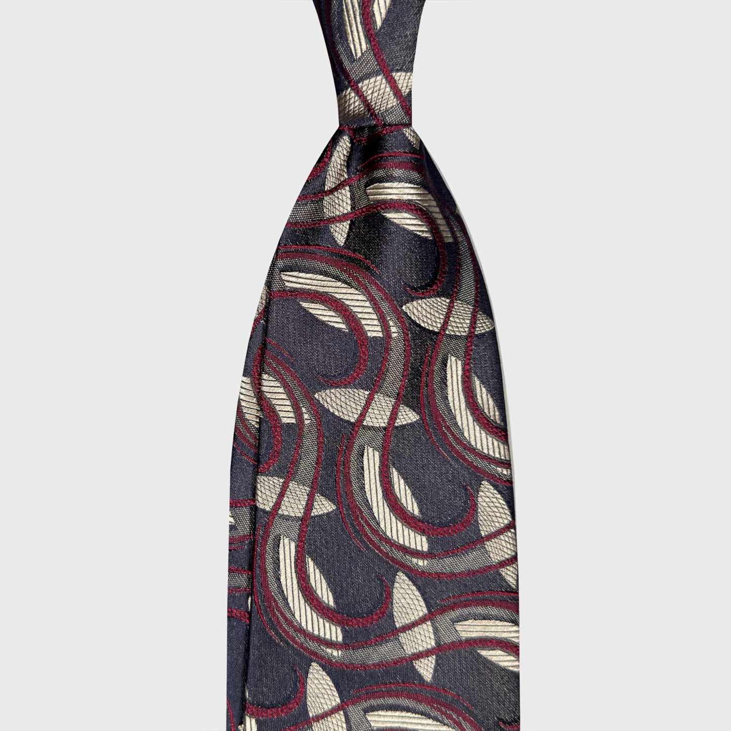 Anthracite Grey Silk Tie Art Nouveau Ornament Botanic Pattern. Art Nouveau silk tie with ornamental pattern in anthracite grey, ivory beige and ruby red. Ties handmade in Italy and selected by Wools Boutique Uomo Geneva.