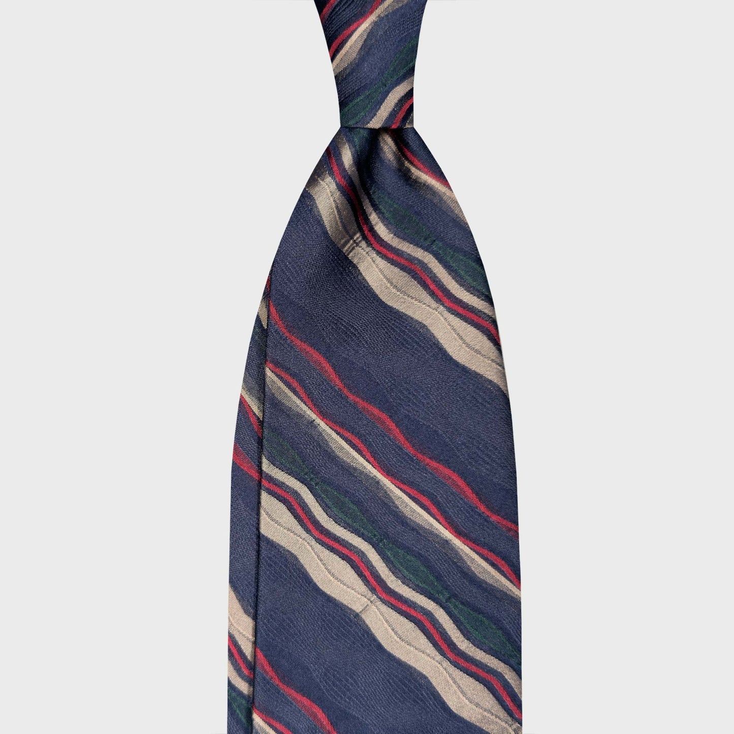 Art Nouveau Wave Stripe Pattern Denim Blue Silk Tie Store Geneva. Denim blue silk tie with Art Nouveau wave stripes in ivory, red and green. Ties made in Italy and selected by Wools Boutique Uomo Geneva.