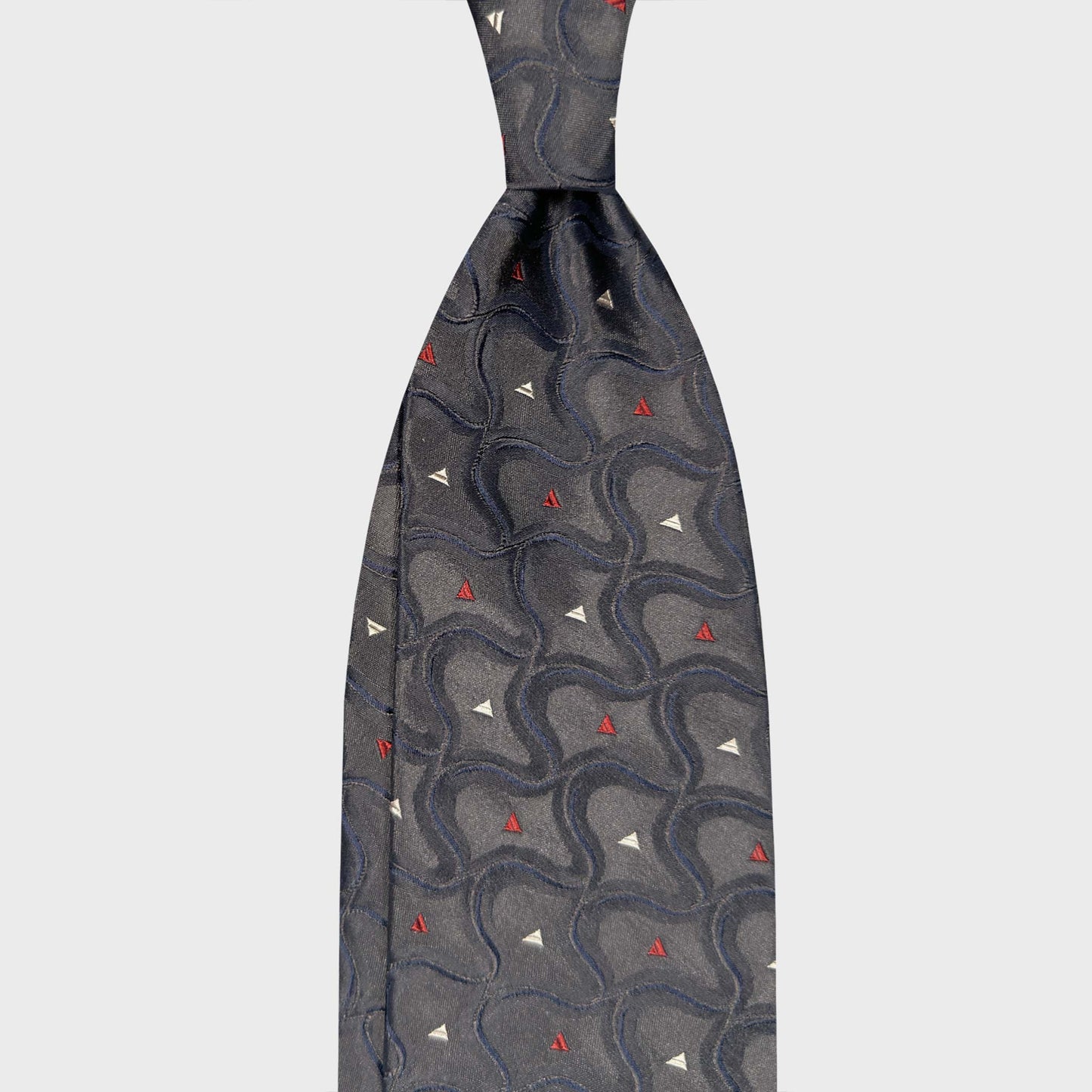 Art Nouveau Geometric Wave Steel Grey Luxury Silk Tie Geneva. Steel grey silk tie with geometric wave pattern in navy blue, ivory and ruby red. Handmade in Italy and selected by Wools Boutique Uomo Geneva Switzerland.
