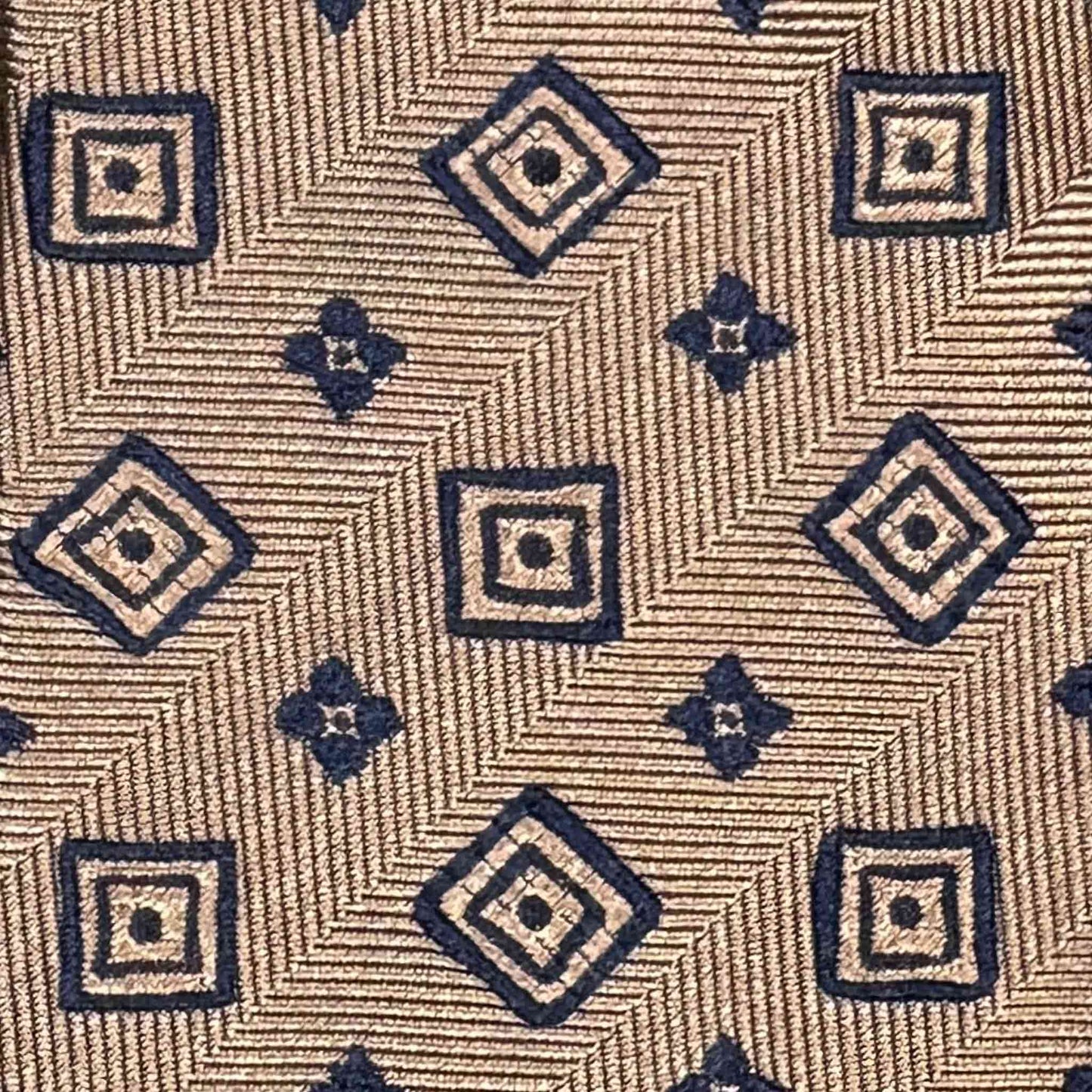 Detail of bronze brown herringbone silk tie with navy blue diamond pattern