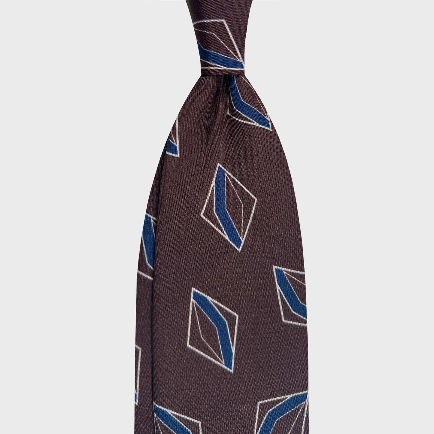 Coffee Brown Silk Tie Art Deco Rhombus Geometric Pattern. Coffee brown silk tie with Art Deco rhombus geometric pattern in blue and white tones. Handmade in Italy for refined contemporary menswear. F.Marino Napoli ties are available at Wools Boutique Uomo Geneva.