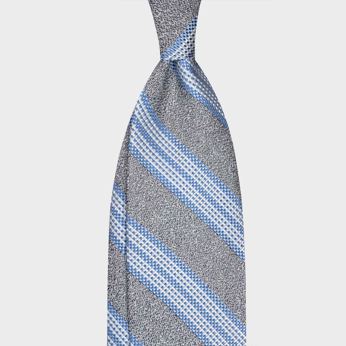 Discover handmade Italian ties at Wools Boutique Uomo Geneva. This F.Marino regimental silk tie in ash grey and sky blue adds refined elegance to business and sartorial outfits.
