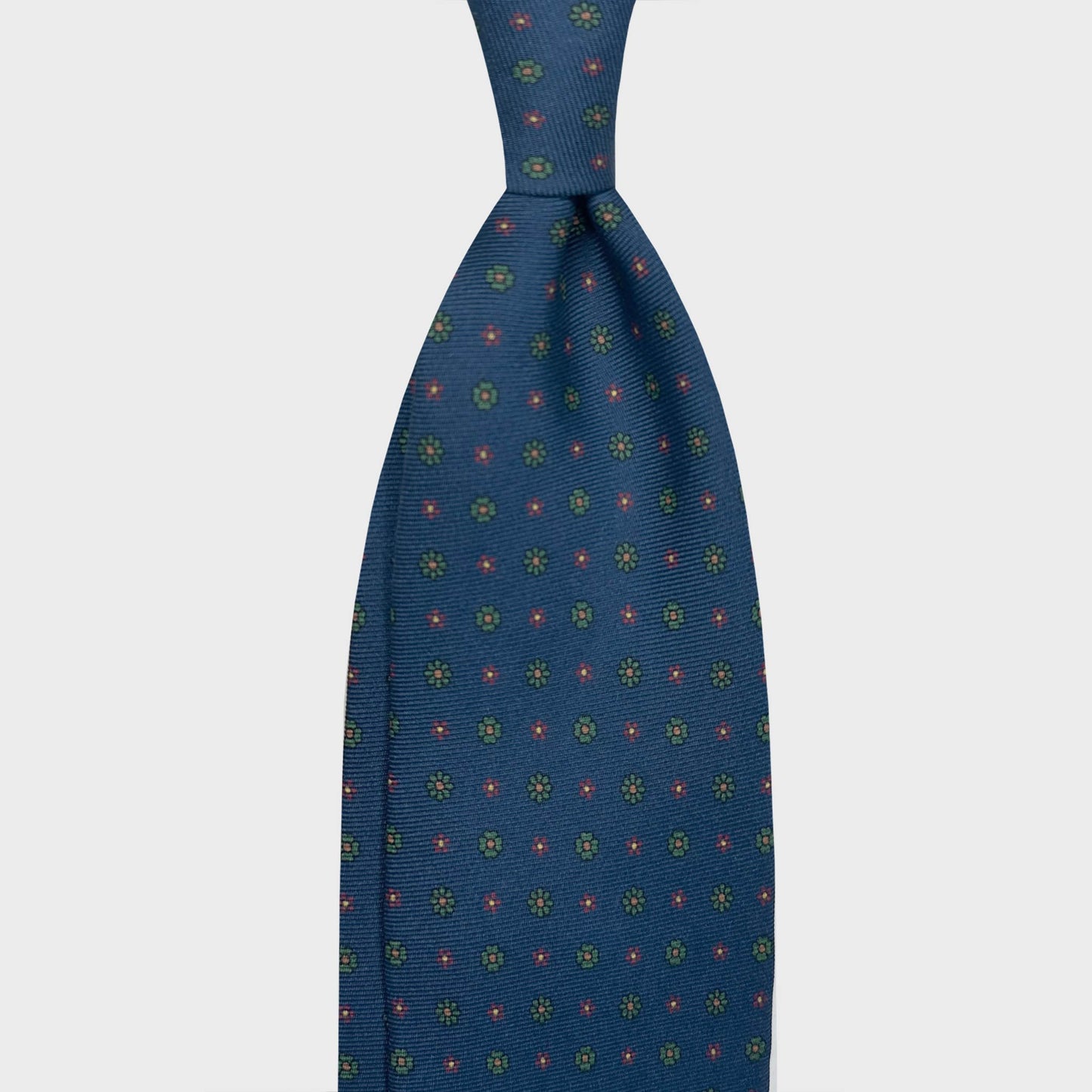 Classic Silk Tie 7 Folds Grass Green Burgundy Daisy. Elegant blue silk tie with denim blue background, grass green and burgundy micro daisy pattern, madder seven folds silk ties Wools Boutique Uomo Genève