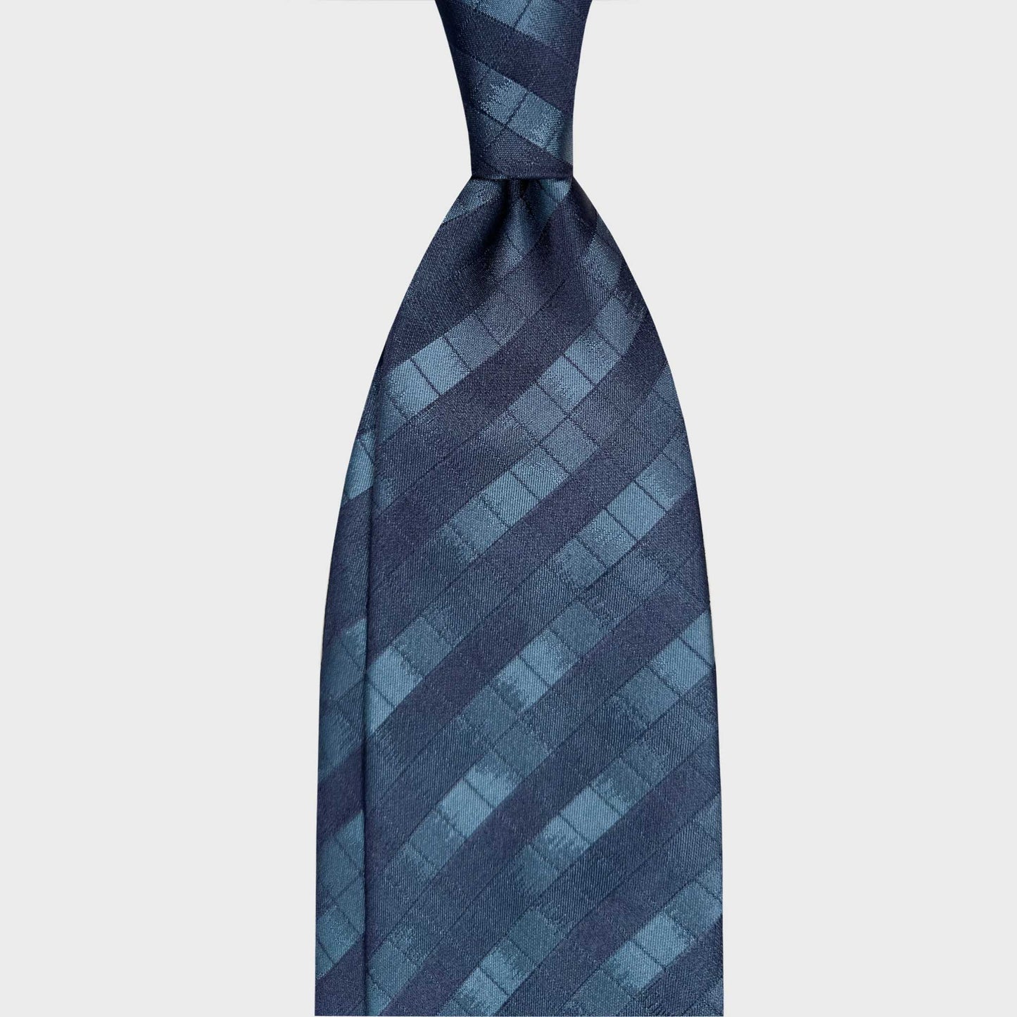 Blue silk tie featuring a windowpane checked pattern in navy, sky blue and petrol tones. A refined geometric design ideal for elegant business attire and contemporary sartorial styling.