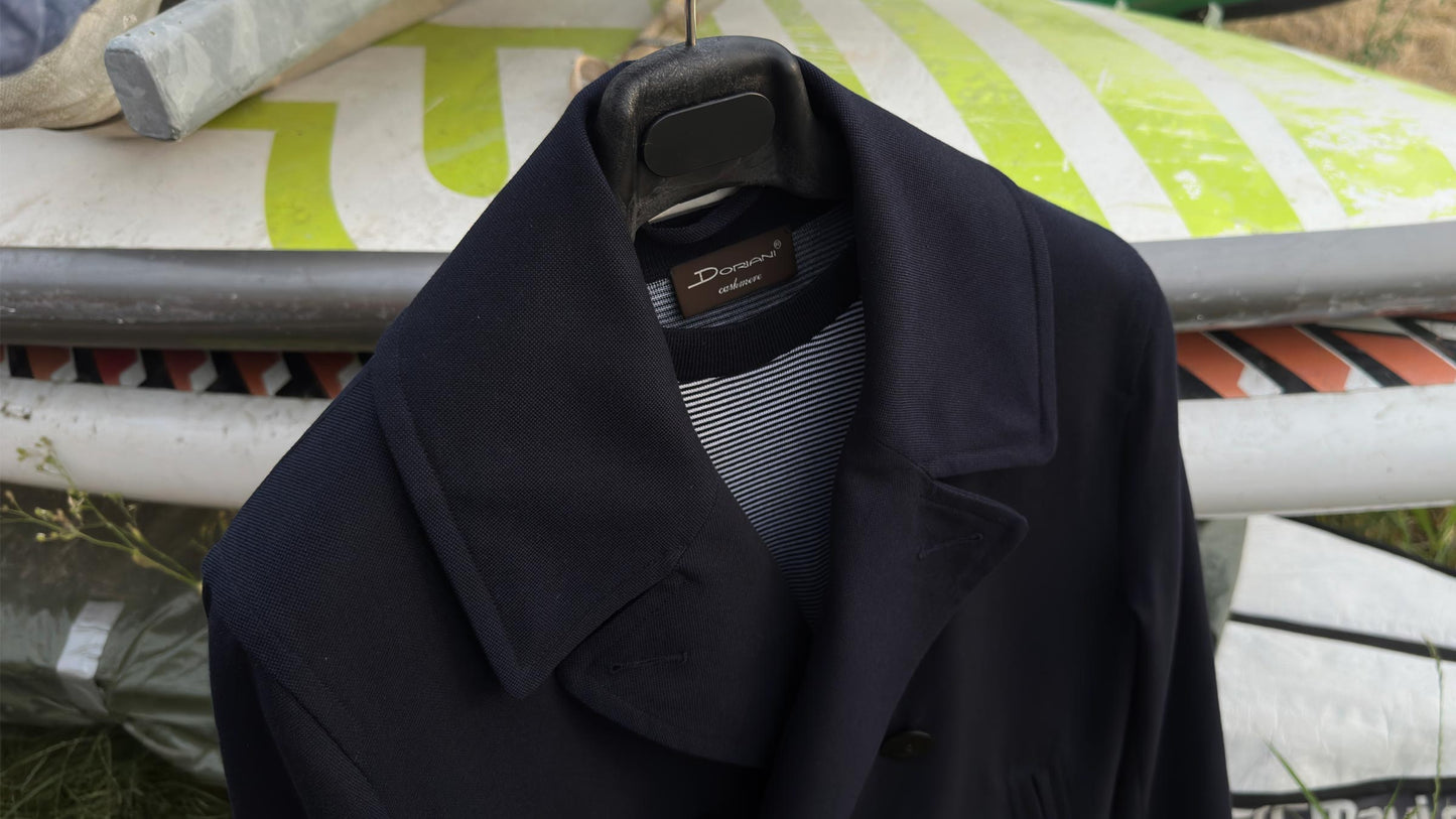 Navy overcoat layered over a classic marinière striped knit for elegant men's style