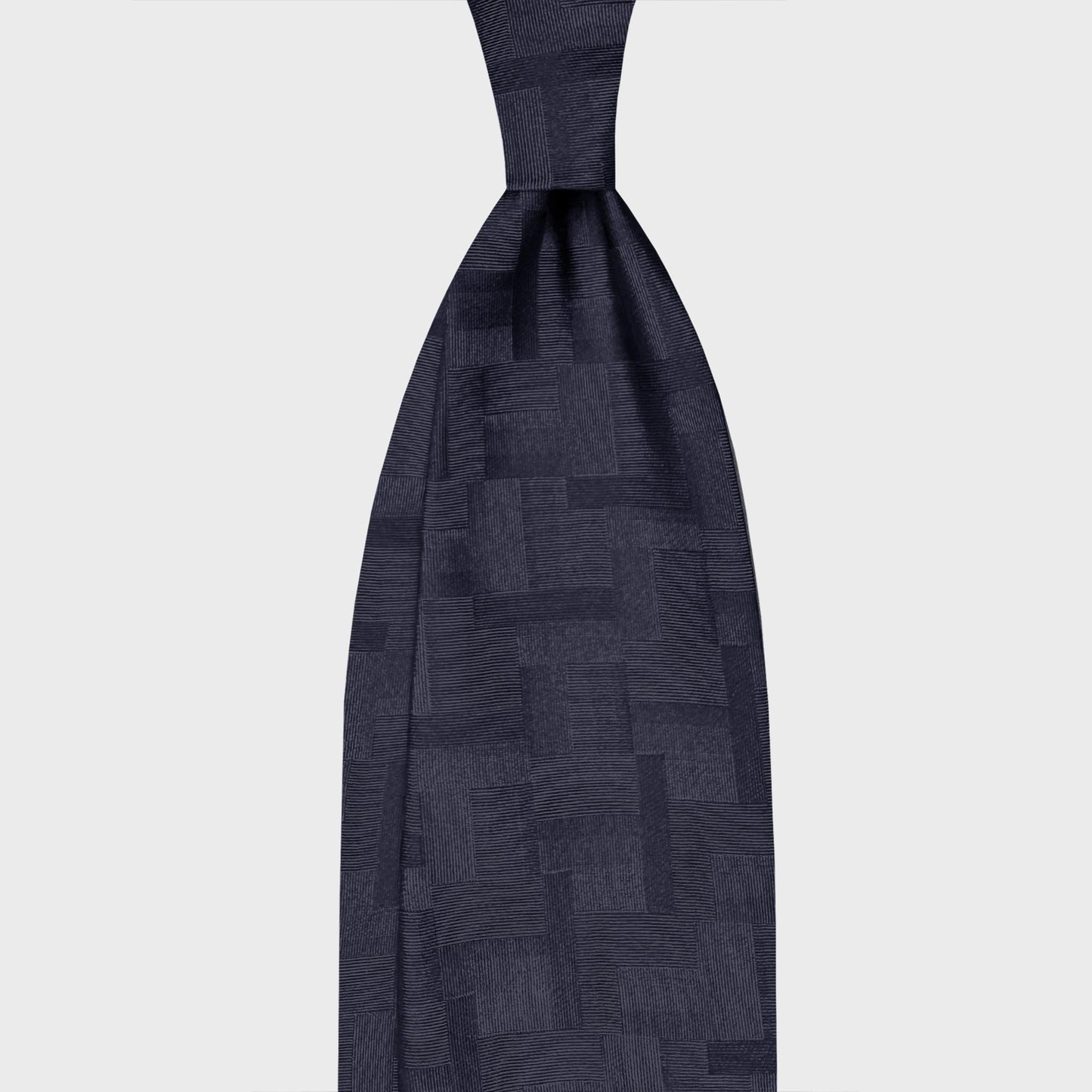 Navy Blue Silk Tie Geometry Patchwork Pattern. Navy blue satin silk tie with a refined jacquard design with architectural character, ideal for contemporary business and elegant formal menswear.