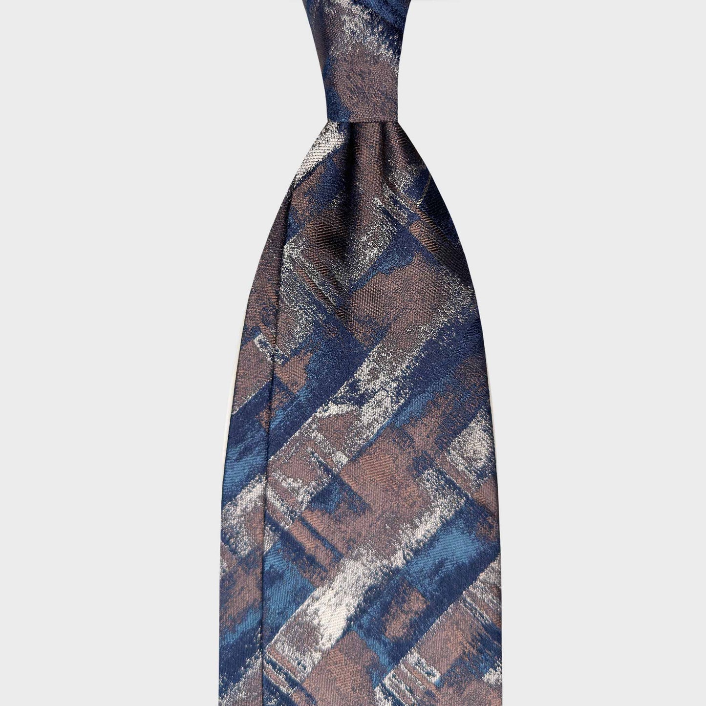 Bronze silk tie featuring an abstract artistic jacquard design in navy, petrol blue and silver tones. A refined statement piece crafted in Italy, ideal for contemporary formal wear and distinctive sartorial styling.