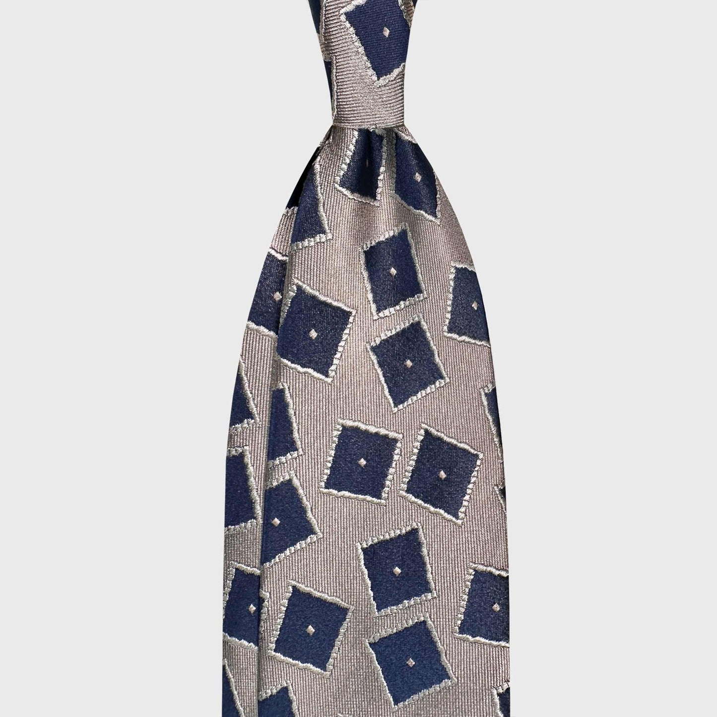 Ivory silk tie featuring navy blue square medallions on a refined greige background. A sophisticated geometric design crafted in Italy, ideal for elegant business attire and contemporary formal looks.
