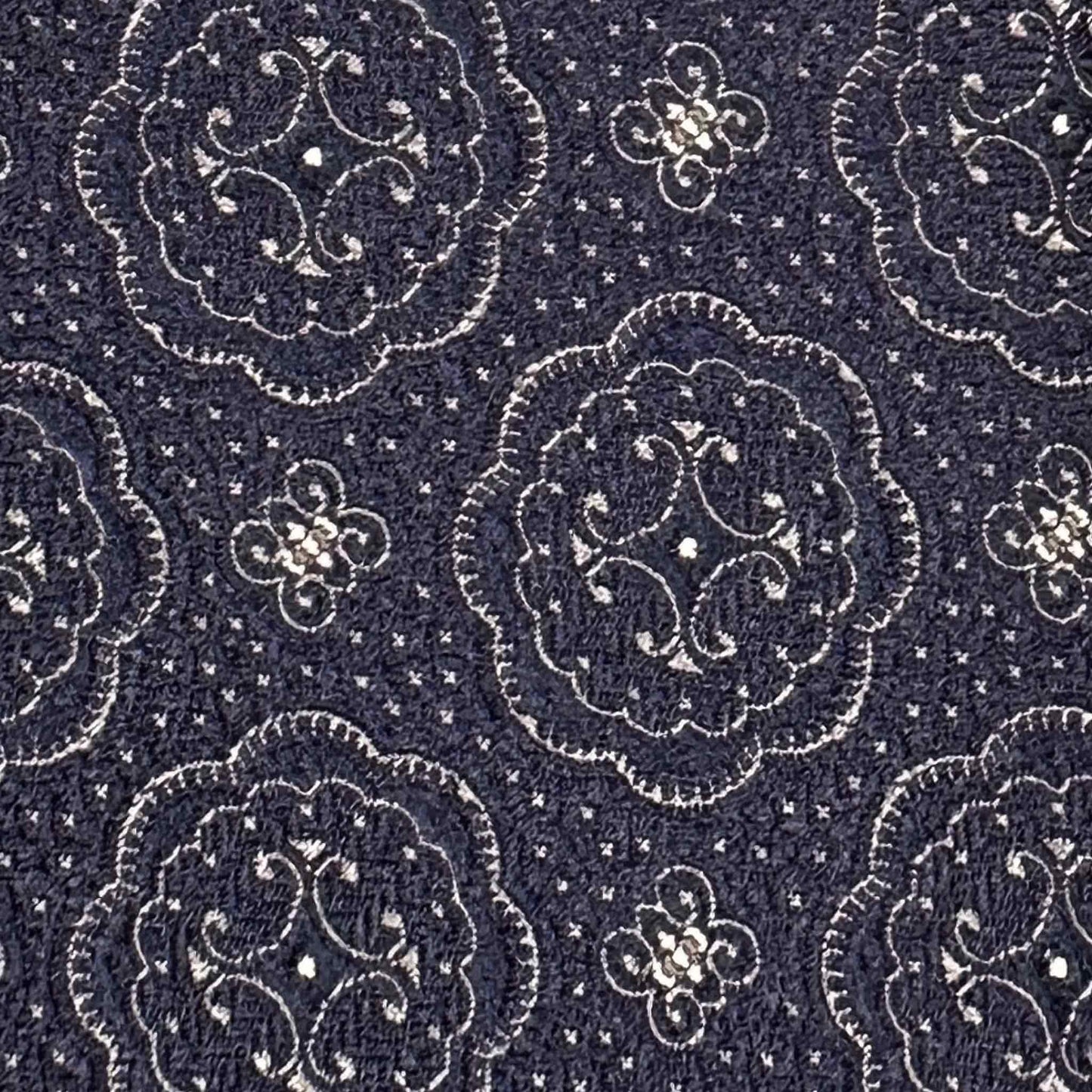 Detail of white medallions and micro-pattern texture on navy blue silk tie