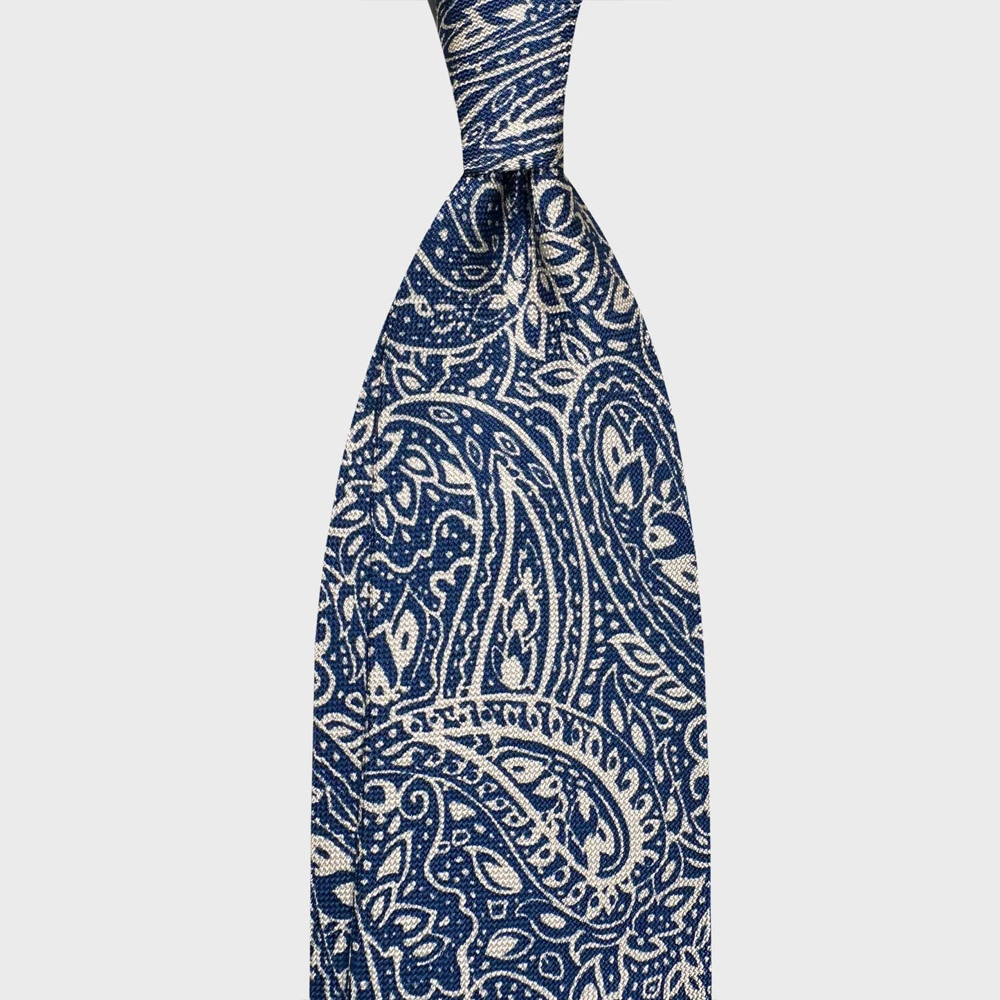 Ivory Panama Silk Tie Bold Paisley Design. Ivory silk tie in soft panama silk featuring a bold navy blue paisley motif. Lightweight and refined, ideal for elegant spring and summer tailoring. Wools Boutique Uomo men's store in Geneva.