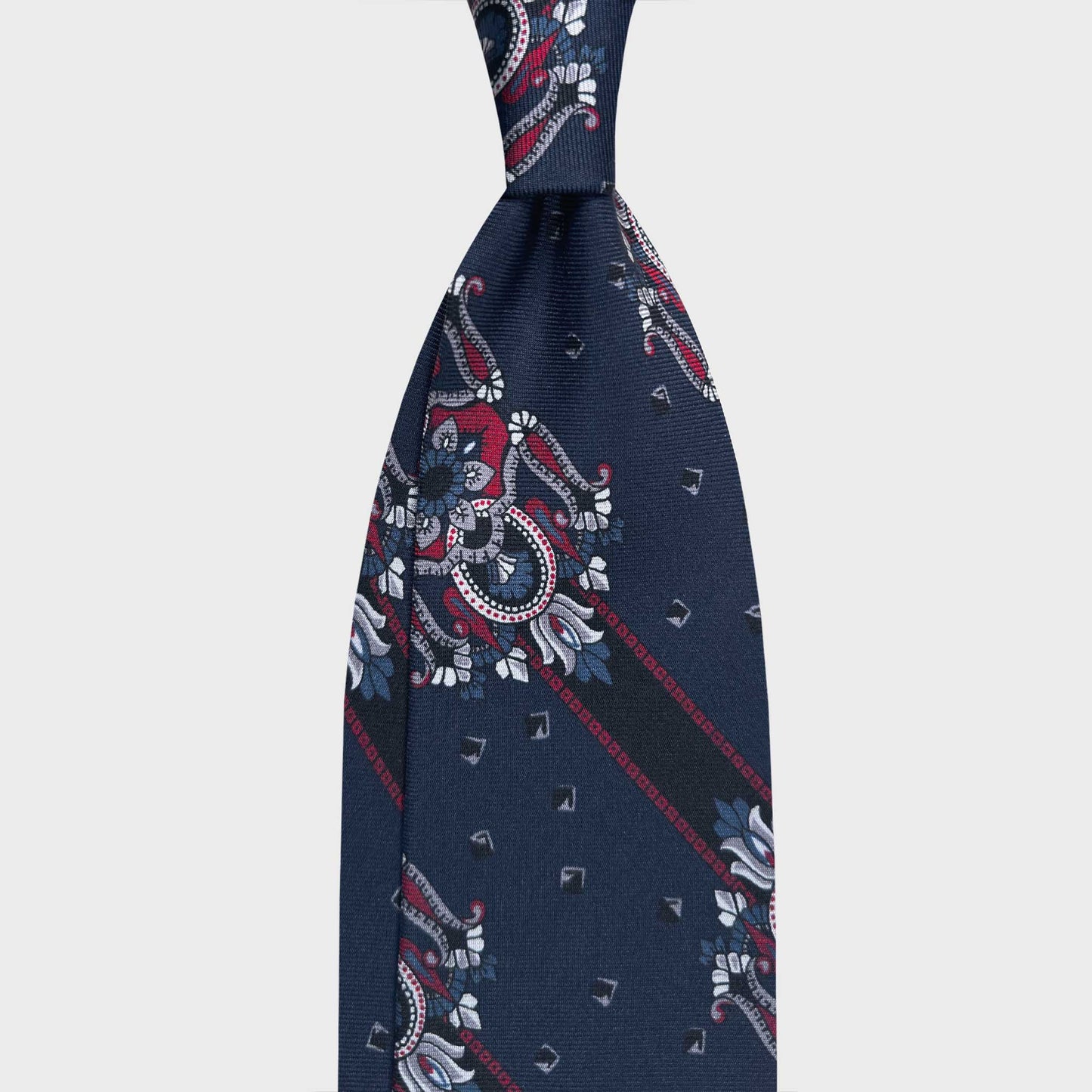 Dark Denim Blue Silk Tie Regimental Ornamental Design. Silk tie featuring a refined regimental ornamental motif on denim blue background with burgundy and ivory. Handmade in Italy for timeless sartorial elegance. F.Marino Napoli handmade ties available at Wools Boutique Uomo Geneva.
