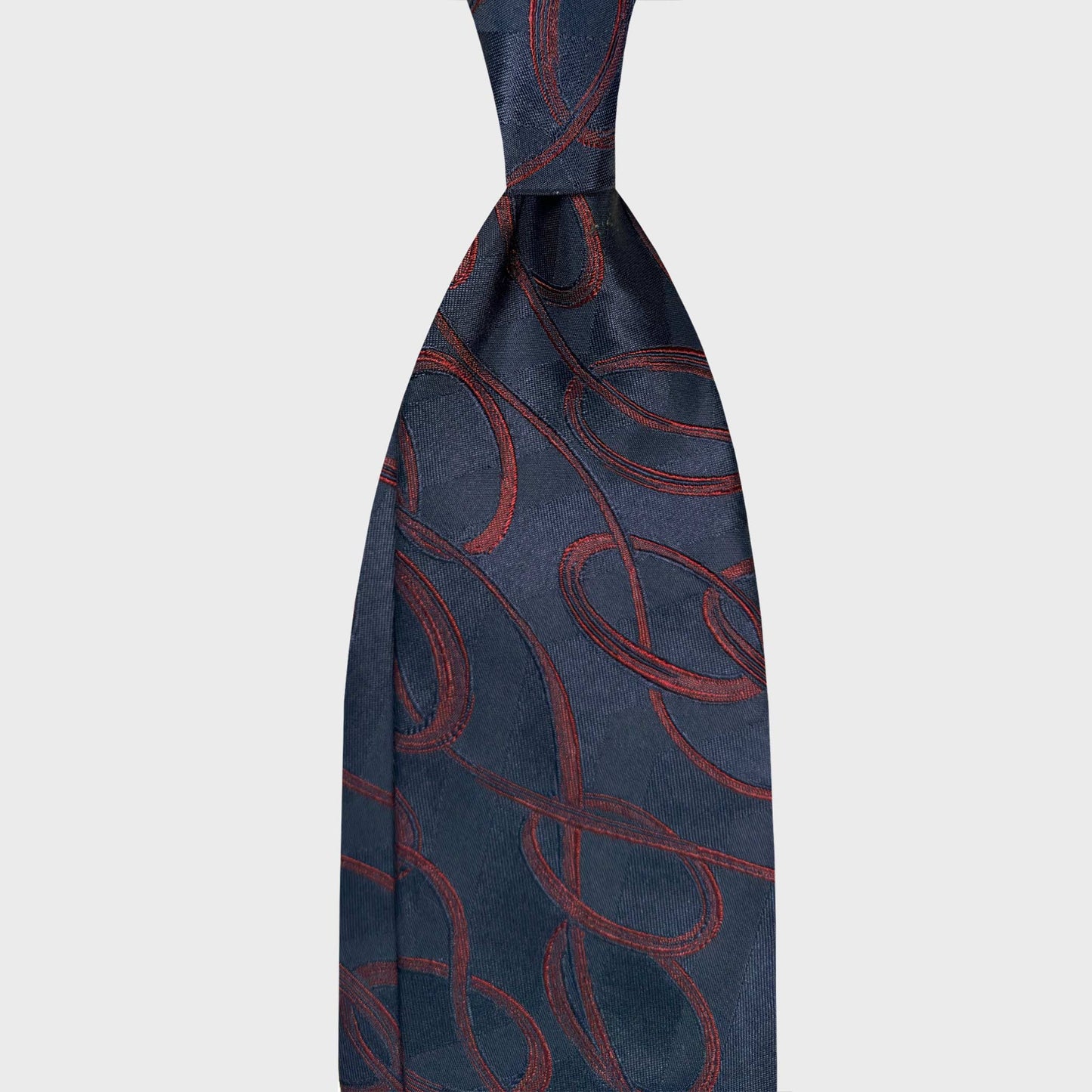 Navy blue satin silk tie featuring a graphic Art Nouveau design in deep red tones. Fluid lines and refined texture create a sophisticated statement for elegant business attire and evening menswear.