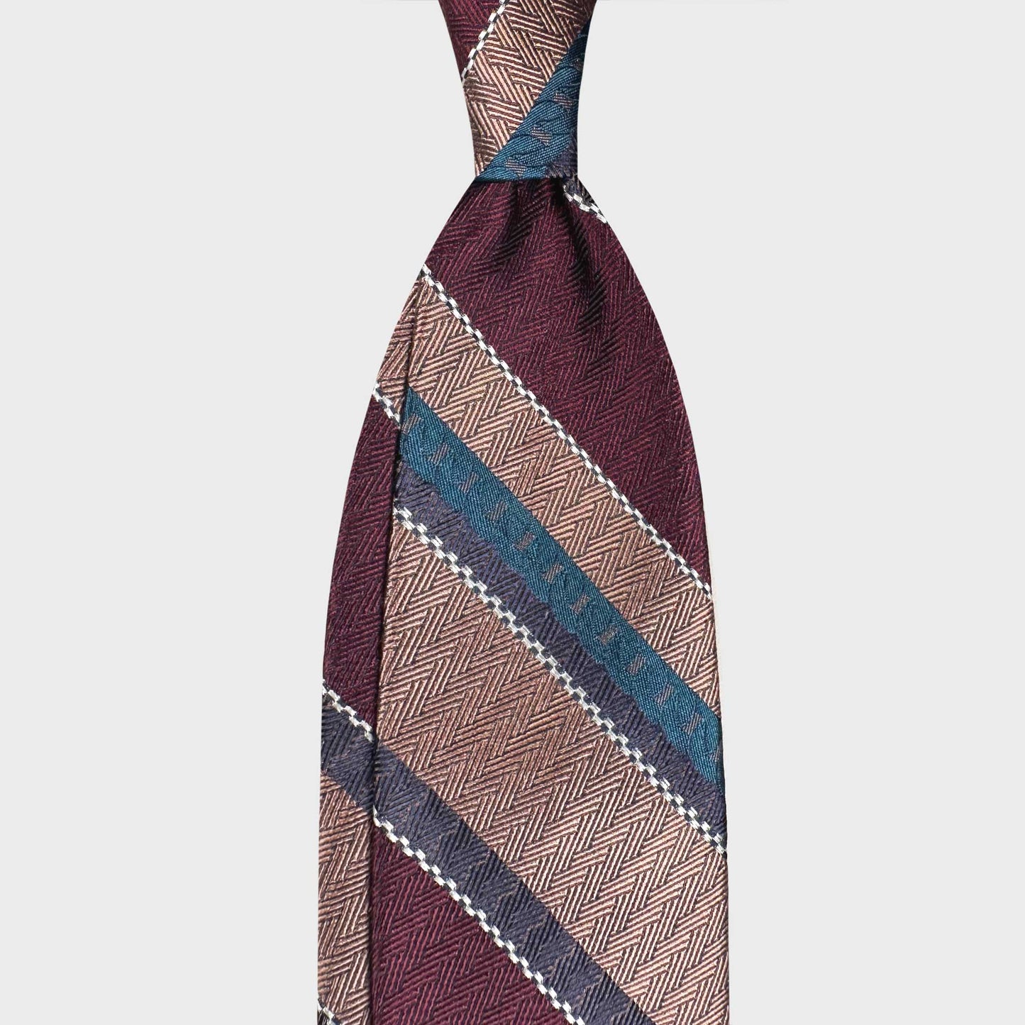 Explore refined Italian neckwear at Wools Boutique Uomo Geneva. This F.Marino regimental silk tie in burgundy, gold and teal is handmade in Italy and ideal for classic business tailoring.
