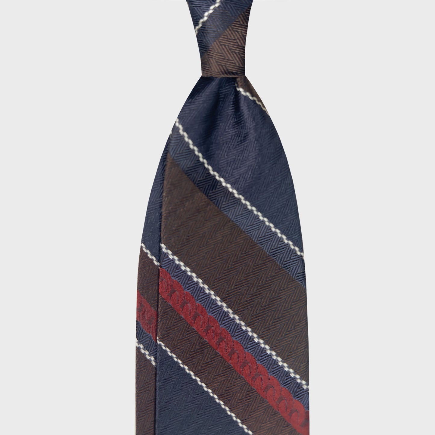 Regimental Herringbone Jacquard Silk Tie Embroidered Stripe . Regimental silk tie in herringbone jacquard with embroidered stripe detail. Denim blue and coffee brown tones. Handmade in Italy ties at Wools Boutique Uomo.