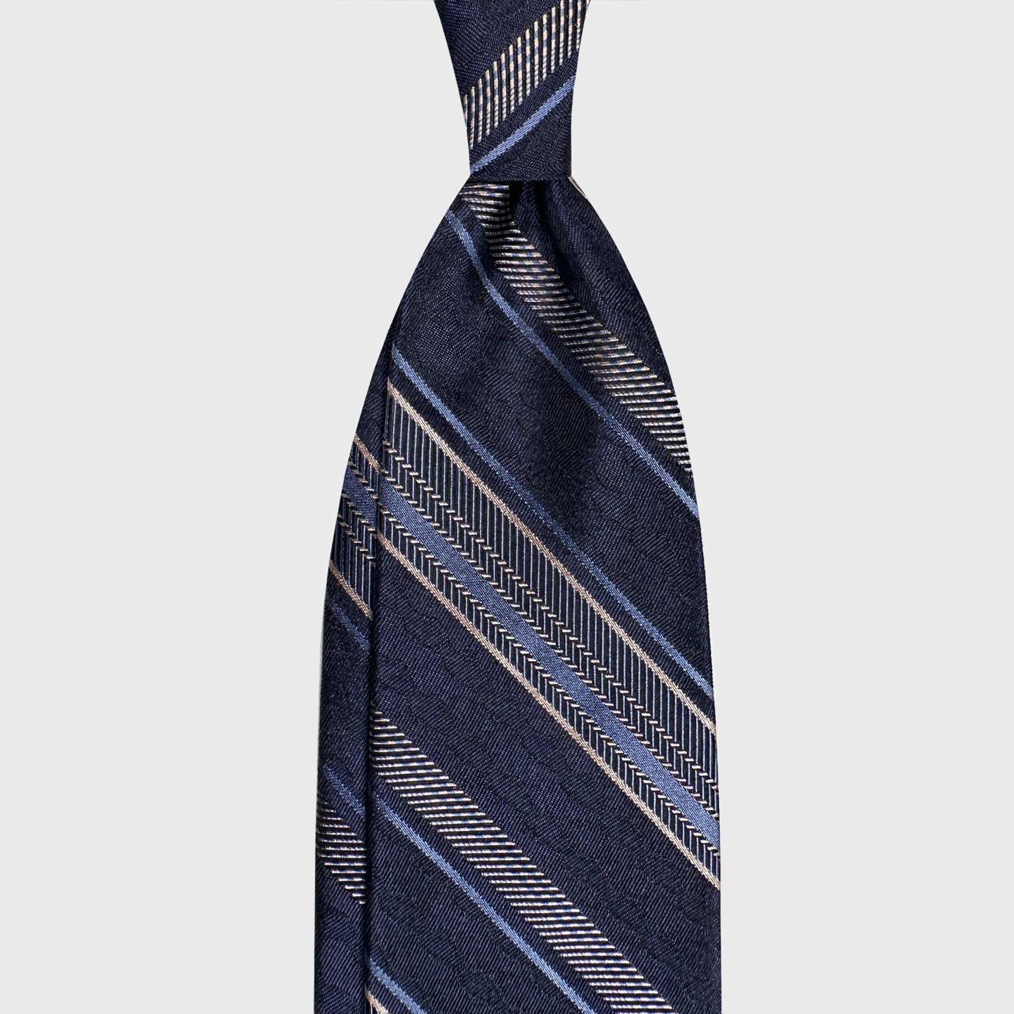 Discover refined Italian ties at Wools Boutique Uomo Geneva. This F.Marino silk regimental tie in navy blue with sky blue and silver stripes is a timeless choice for business and professional tailoring.