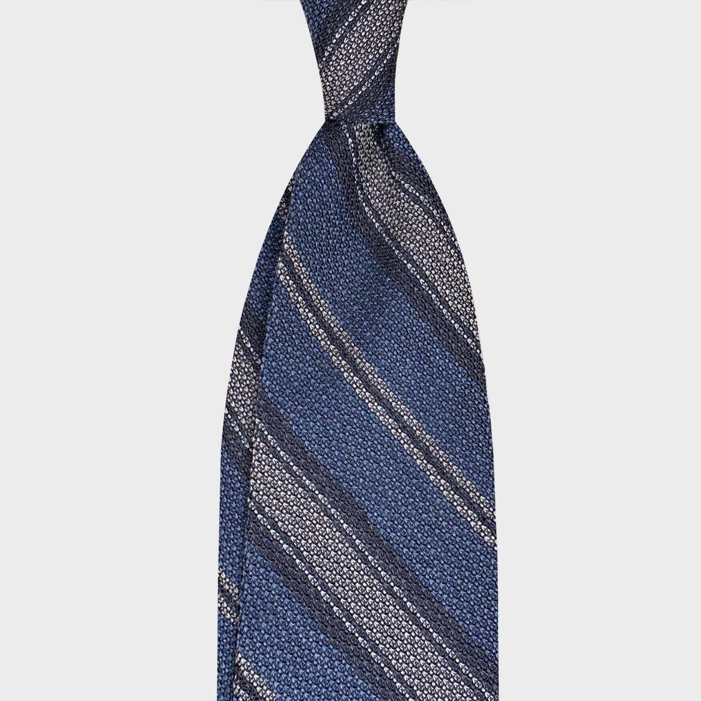 Handmade F.Marino grenadine silk regimental tie in denim blue with silver stripes. Crafted in Naples and available at Wools Boutique Uomo Geneva.