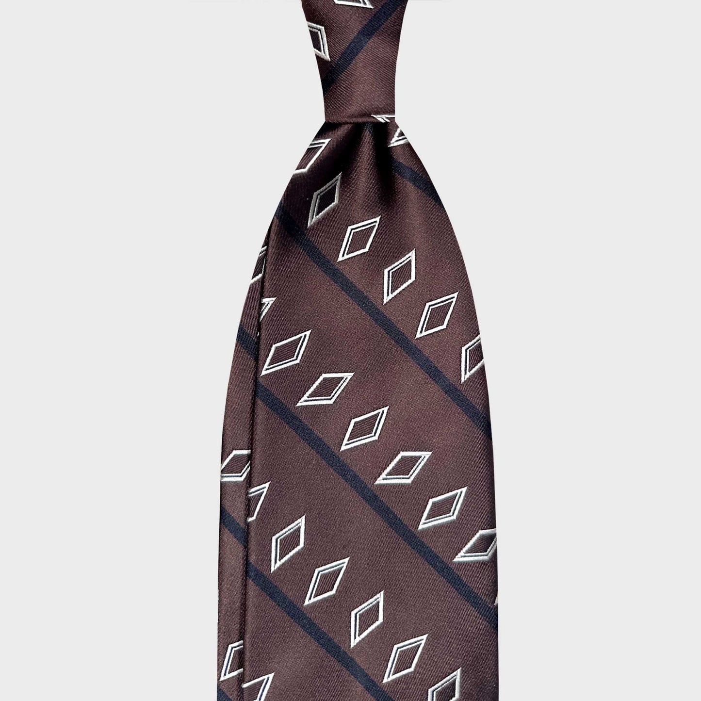 Coffee Brown Regimental Satin Silk Tie White Diamond Pattern.
Elegant brown regimental silk tie with geometric diamond pattern. Discover Wools Boutique Uomo, a luxury Italian made tie store in Geneva, Switzerland.