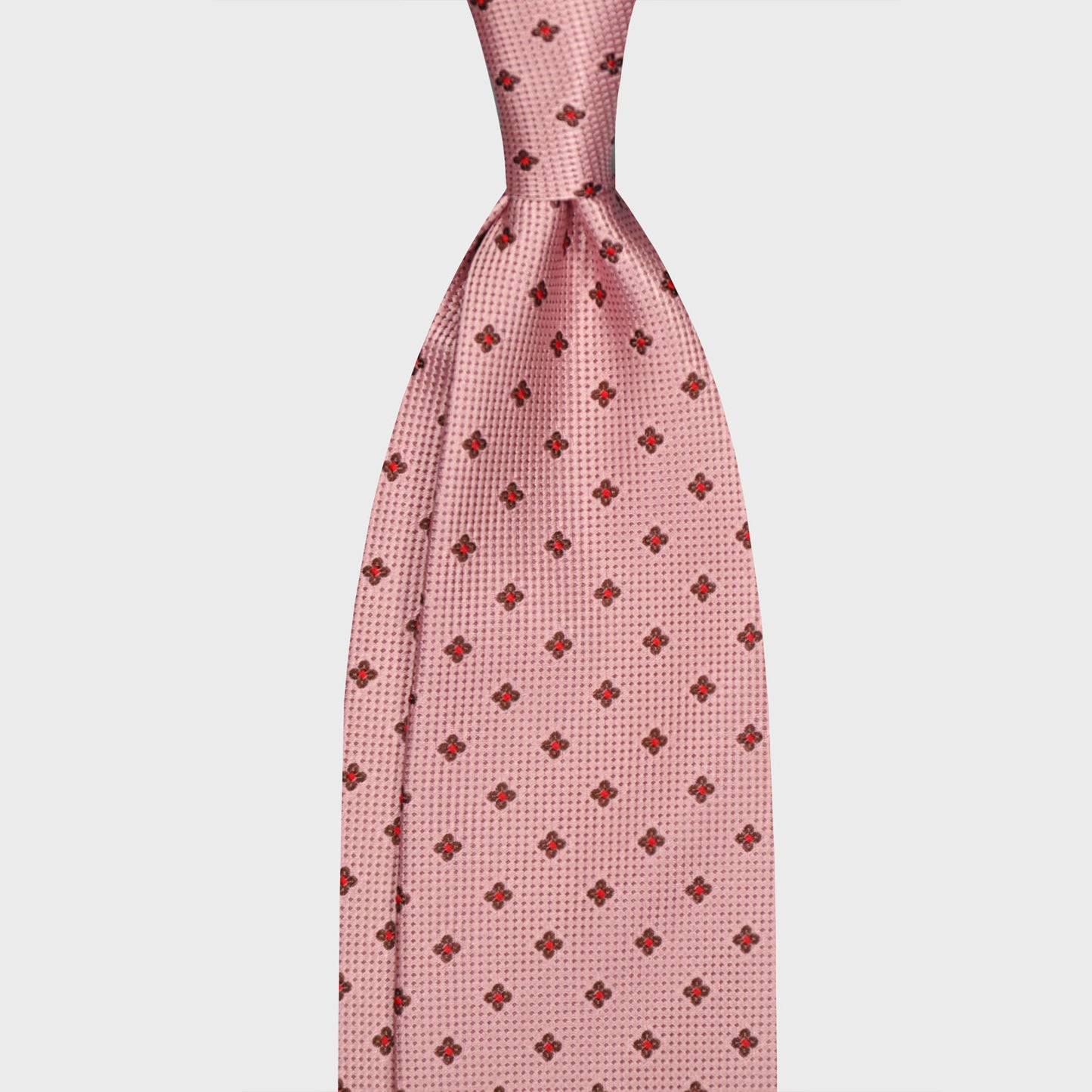 Light pink silk tie featuring a refined micro floral pattern in ruby red and brown. An elegant Italian design ideal for sophisticated business and formal sartorial styling. Wools Boutique Uomo men's ties store in Geneva.